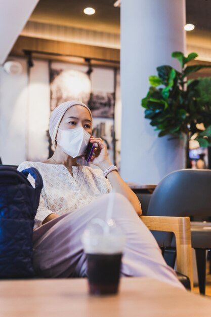 Woman wearing protective face mask talking on mobile phone in cafe