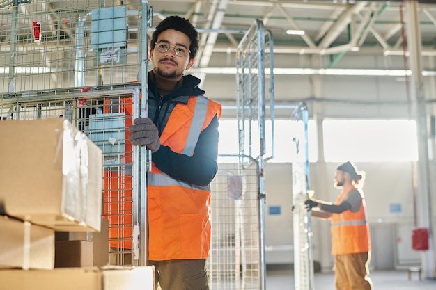 Young male worker of warehouse in eyeglasses gloves and safety vest