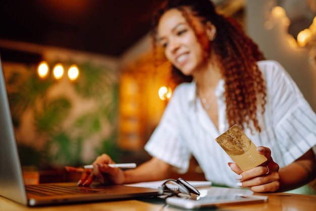 Young woman sitting at cafe making online shopping using credit card and laptop Online shopping