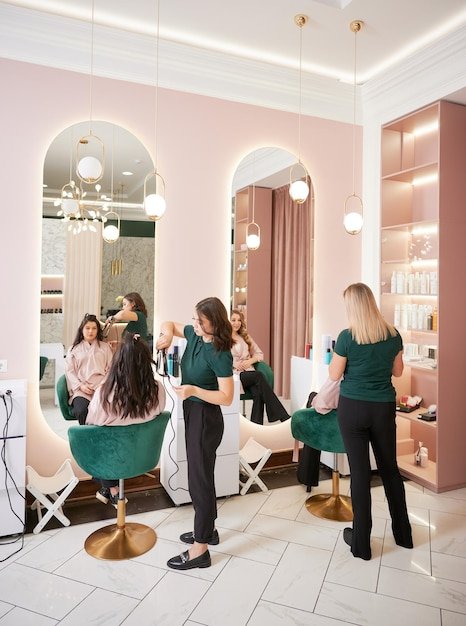 Hairdressers styling women hair in beauty salon
