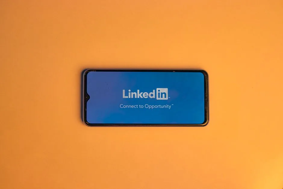 Smartphone showing LinkedIn login on vibrant orange background, symbolizing connectivity.
