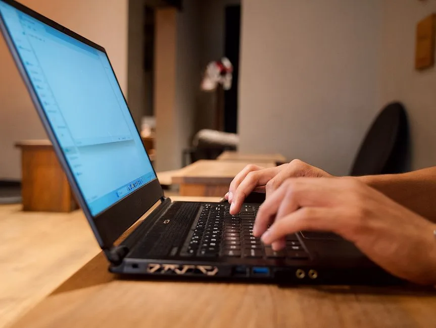 Hands typing on a laptop in a modern office setting, perfect for illustrating work or productivity concepts.