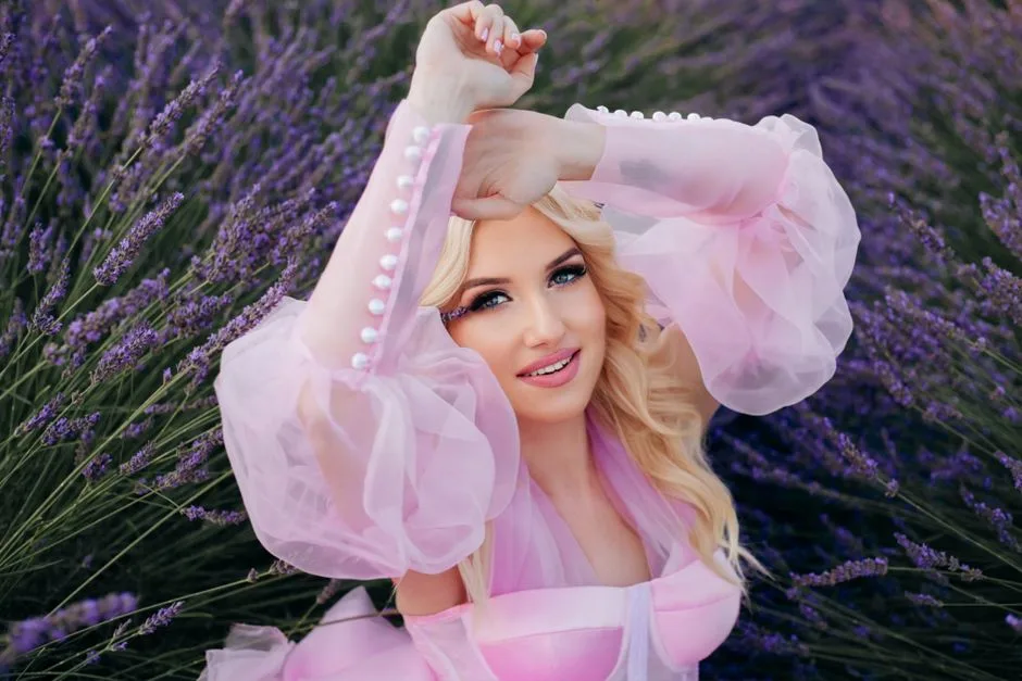 A beautiful woman in a pink dress posing gracefully in a lavender field, exuding charm and elegance.