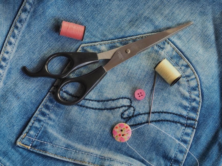 Colorful sewing supplies arranged on blue denim fabric. Ideal for crafting themes.