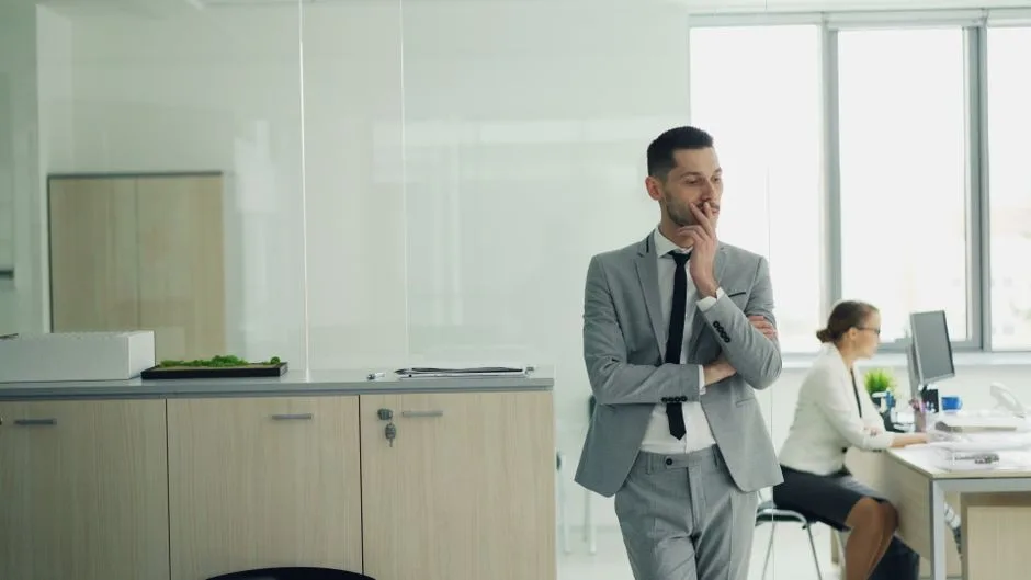 Businessman in suit thinking with colleague working in a modern office.
