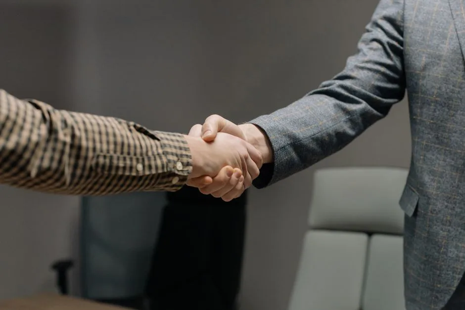 Close-up of two professionals shaking hands in an office, symbolizing successful business dealings.