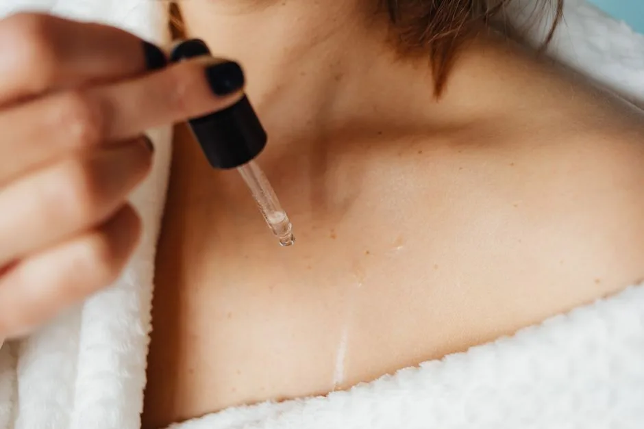 A woman applying skin care oil to her collarbone area for self-care treatment.