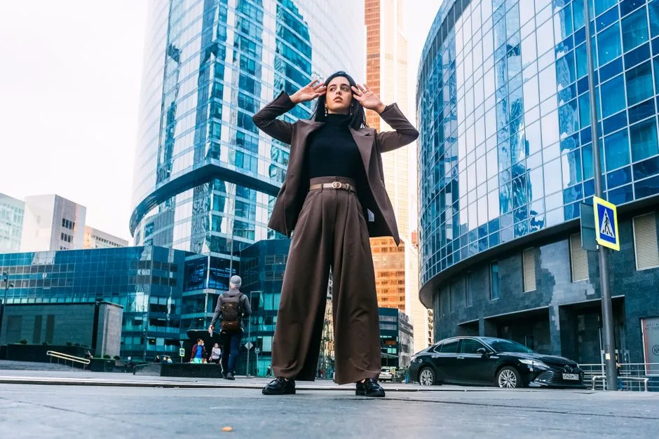 Stylish woman posing in modern Moscow cityscape with skyscrapers, showcasing urban fashion.