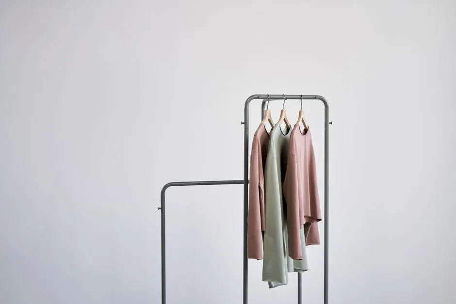 A minimalist fashion photo of casual t-shirts on a clothing rack against a white wall.