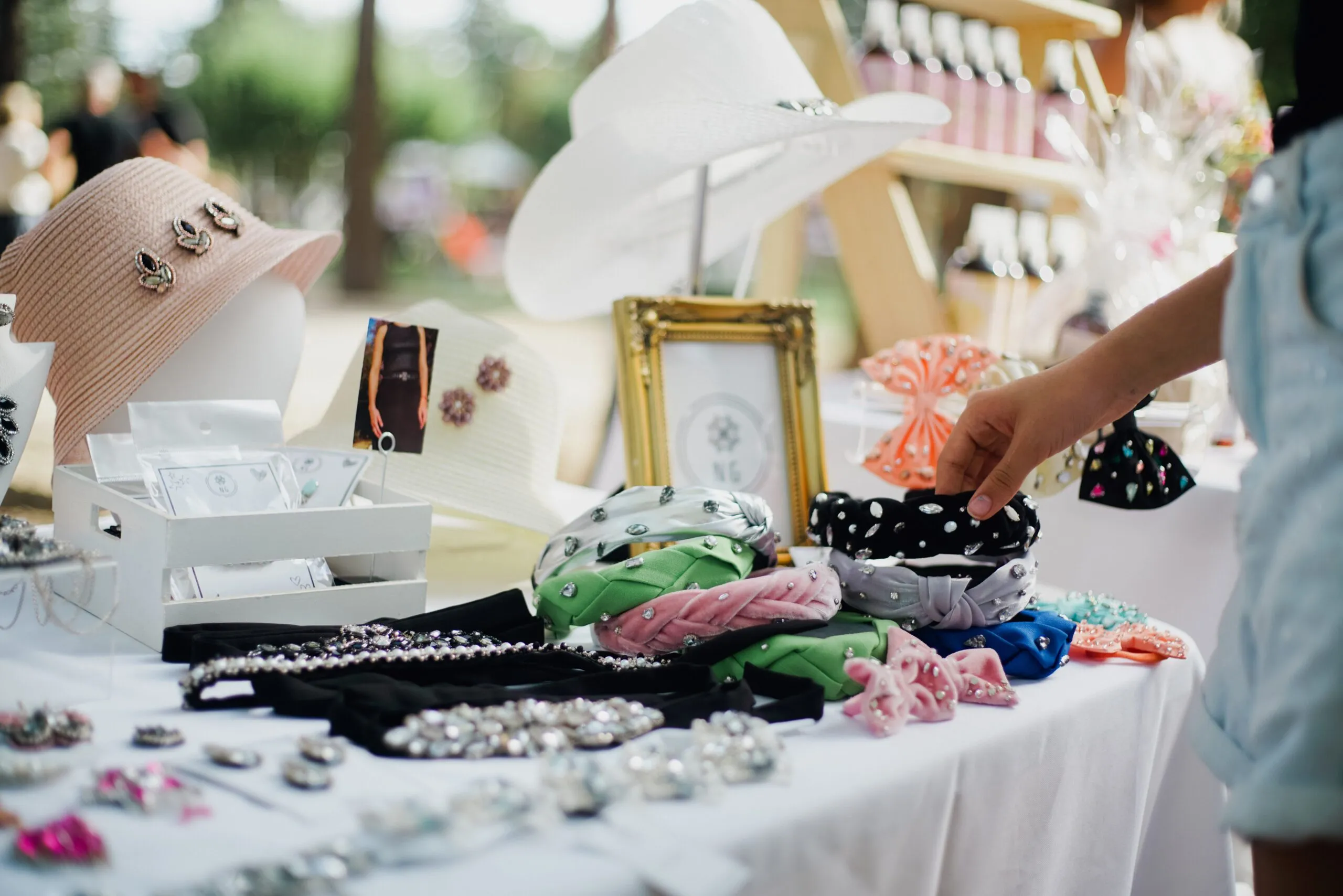 Colorful display of fashion accessories at outdoor market stall featuring hats and headbands.