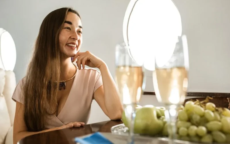 Woman relaxing in a private jet with champagne and fresh fruit, epitomizing luxury travel.