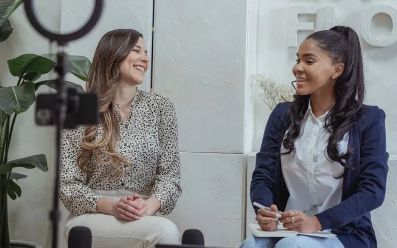 Two women engaged in a lively conversation in a professional interview setting.