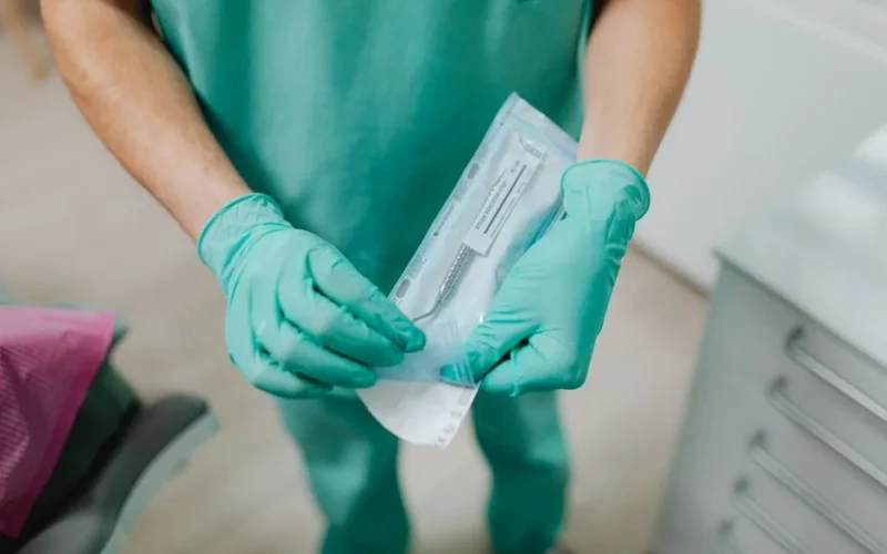 Close-up of a dental professional unpacking sterile instruments in a clinic.