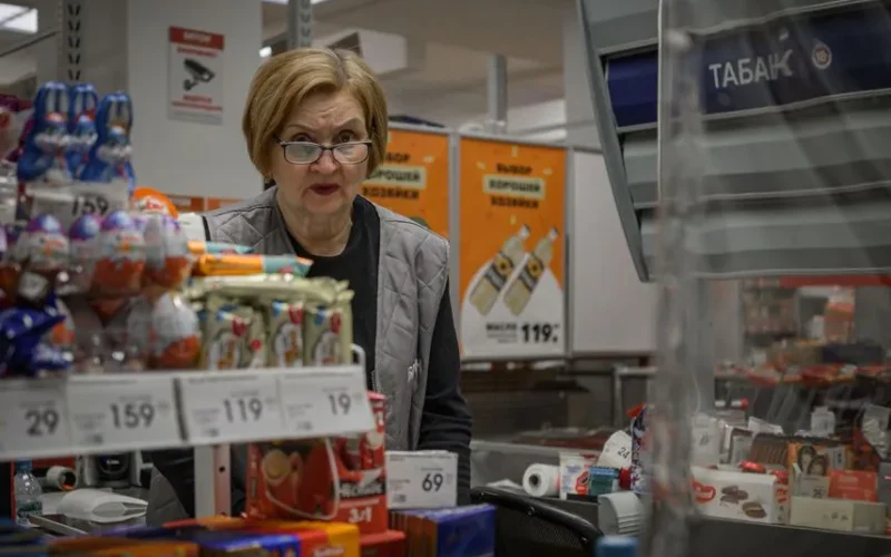 Supermarket scene with cashier and assortment of products at checkout counter.