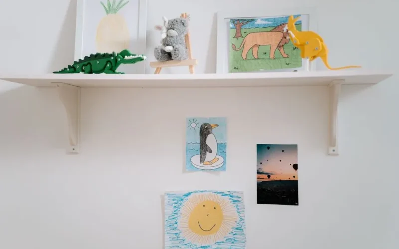 A cozy display of children's artwork and toys on a wall-mounted shelf, capturing creativity and imagination.
