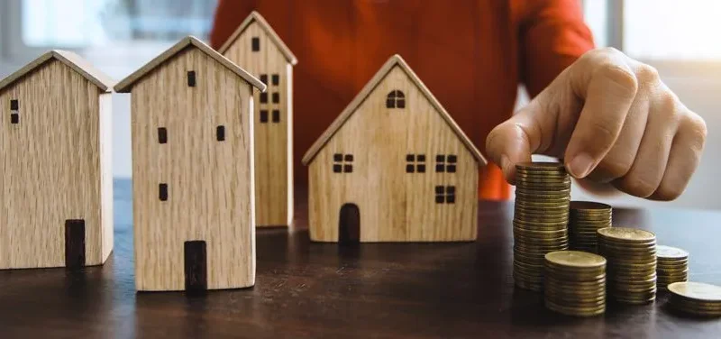 Planning investments with stacked coins and model houses on a table.