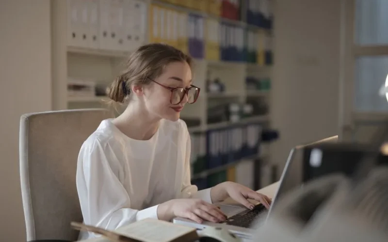 A professional woman concentrating on her laptop at a modern office desk.