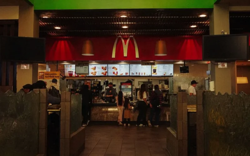 A bustling scene at a McDonald's restaurant counter with customers and staff in an indoor setting.