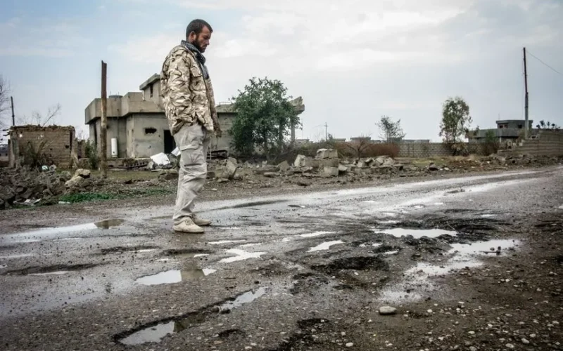 A solitary man walks on a war-ravaged street in Salah ad Din, Iraq amidst destruction.