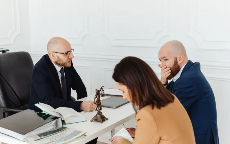 A serious legal consultation in a professional office environment involving three adults.