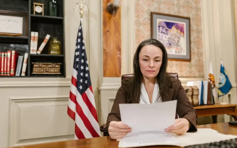 A professional woman reviewing legal documents in an office with flags and books.