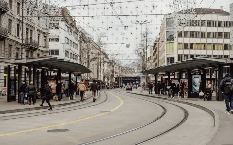 Busy city street in Zürich with tram tracks and people during winter season.