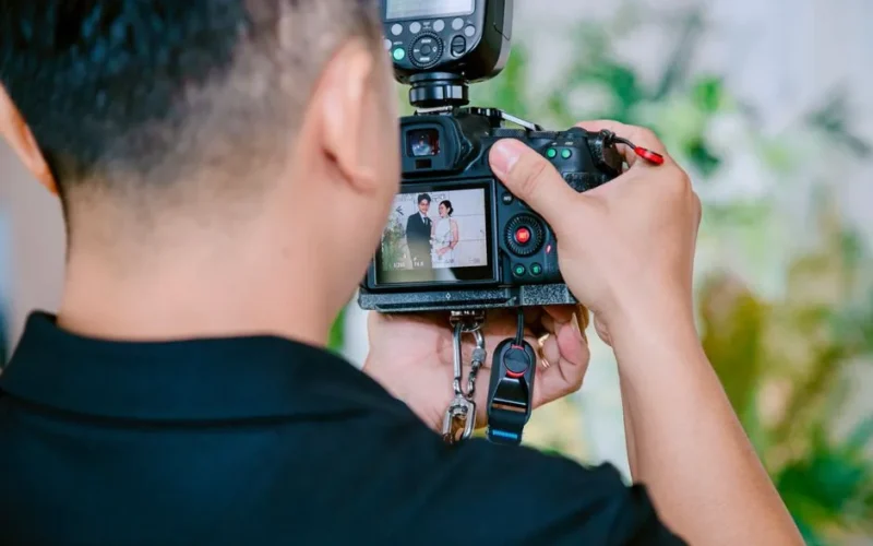 A photographer focuses on capturing a wedding couple using a digital camera during a ceremony.