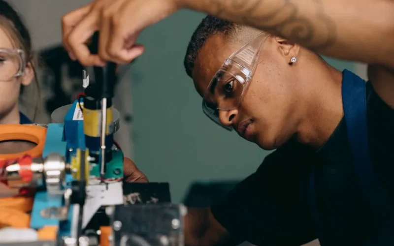 Two young technicians focus on electronic equipment assembly in a workshop setting.