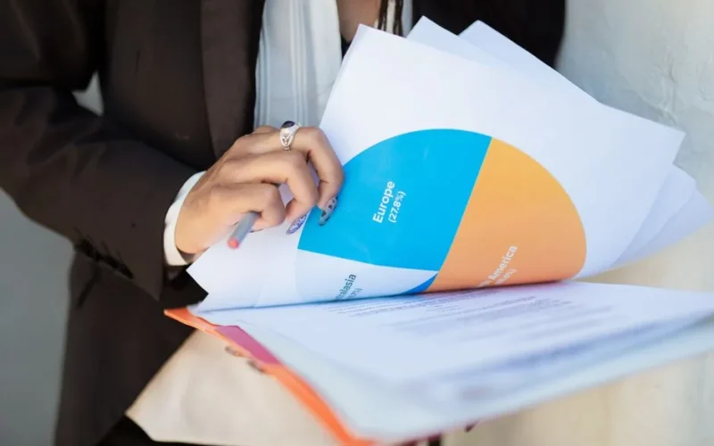 Close-up of a businesswoman reviewing financial documents with a colorful pie chart.