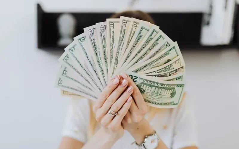 Close-up of hands holding a fan of US dollar bills, showcasing financial abundance.