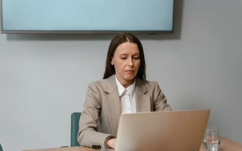 Businesswoman in an office setting focusing on her laptop, conveying professionalism and concentration.