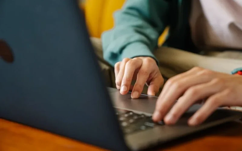 Crop unrecognizable distance employee surfing internet on netbook while working on project at desk in room