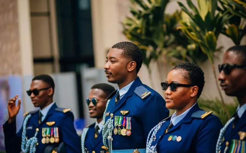 A group of military officers in formal blue uniforms standing outdoors, wearing sunglasses and medals.