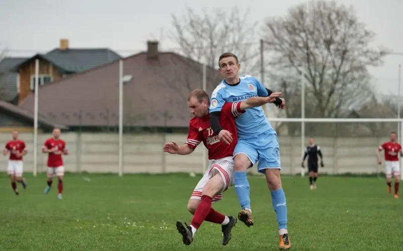 Players fiercely competing in a local football match on an outdoor grassy field.