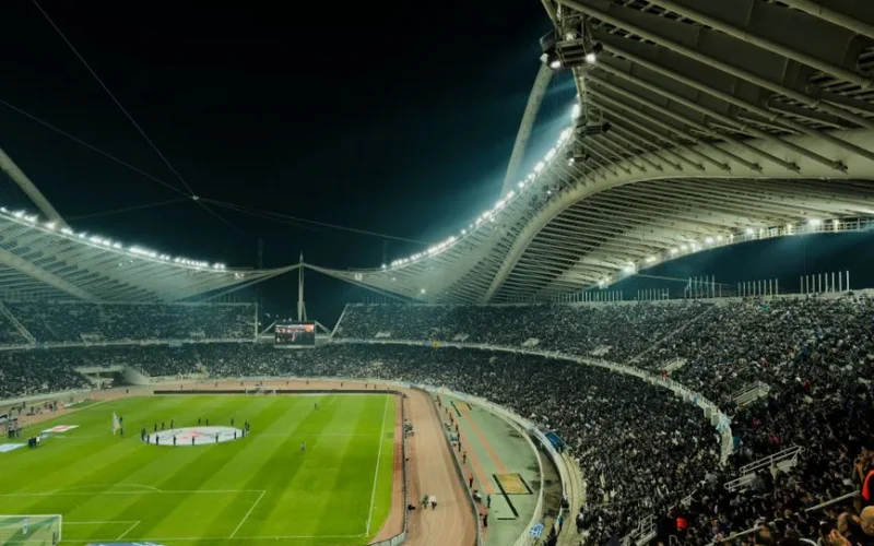 A crowded soccer stadium under bright lights at night, capturing the excitement of a live sports event.