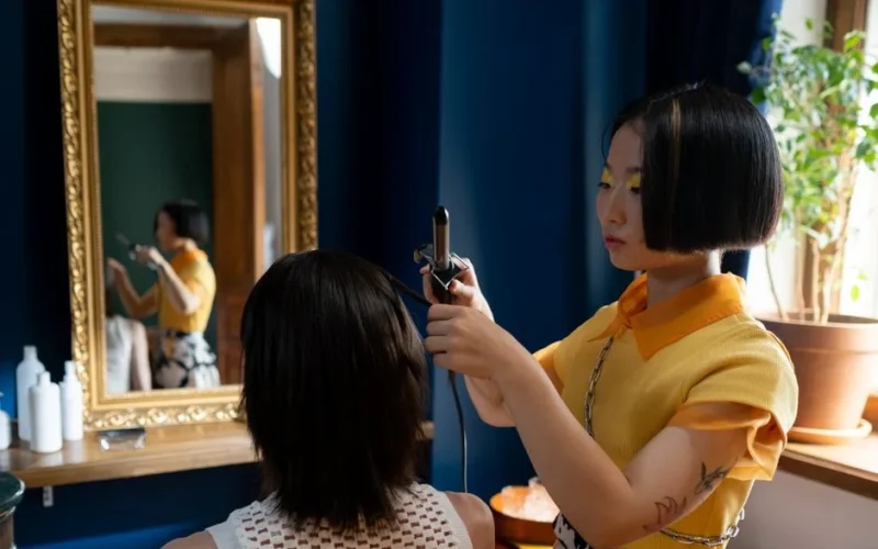Hairdresser styling client's hair in a chic salon with a focus on detailed hair work.