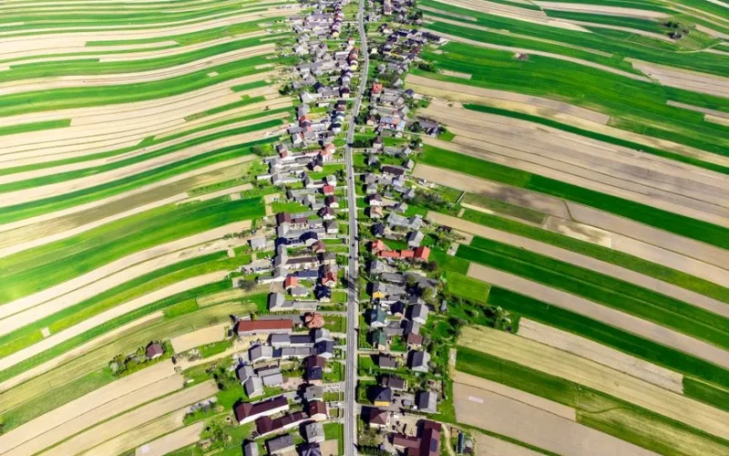 Stunning aerial view of a vibrant Polish village surrounded by lush fields in spring.