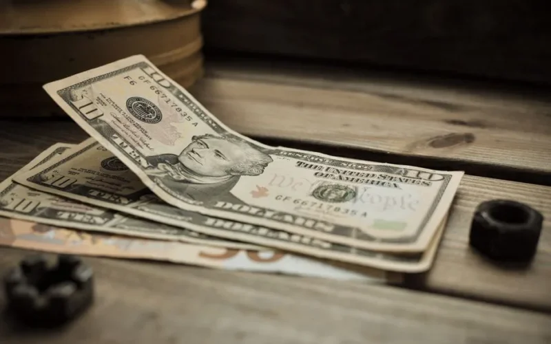 A stack of US dollar bills on a rustic wooden table close-up view.