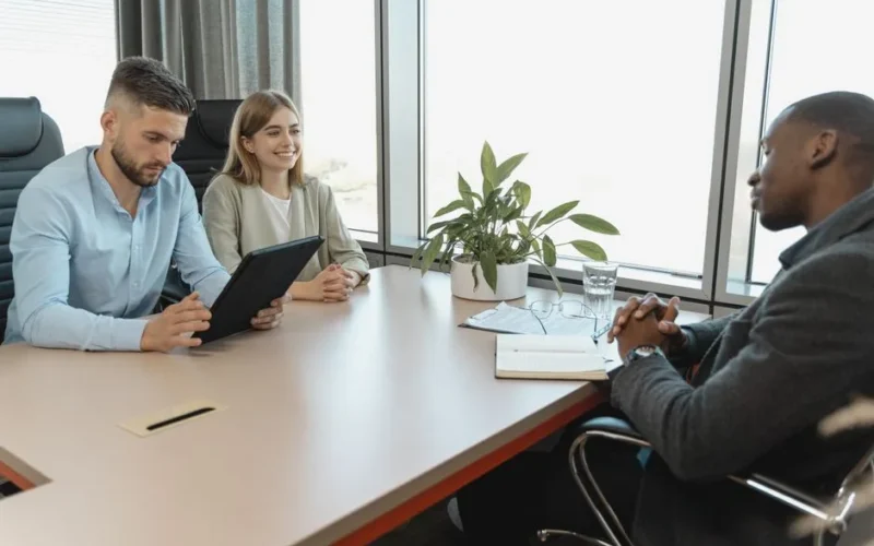 A business interview with three people in a modern office room, highlighting collaboration.