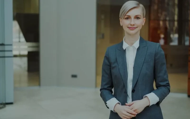 Confident businesswoman in a suit standing indoors in an elegant office setting.