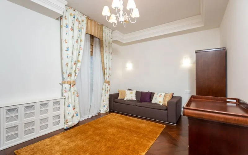 Bright and spacious living room featuring elegant chandelier, cozy sofa, and tasteful decor for a stylish ambiance.