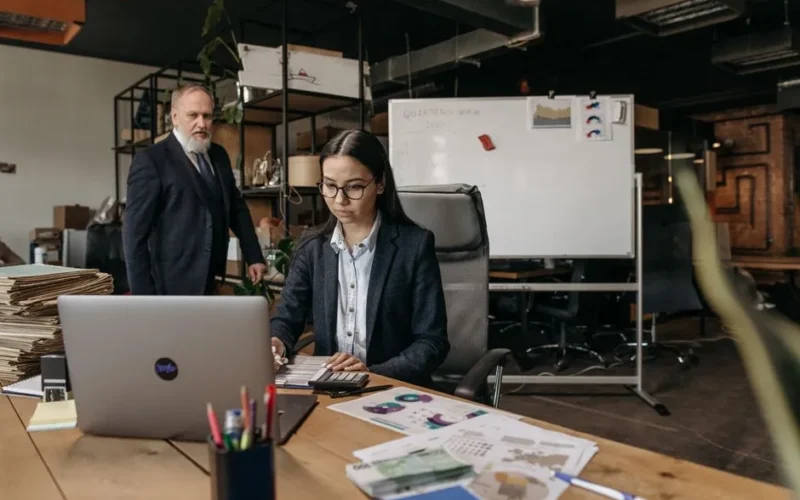 Business professionals collaborating in a modern office setting with laptop and documents.