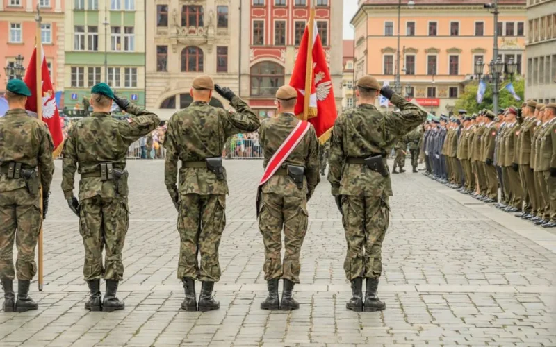 Polish soldiers saluting during a military parade in Wrocław city square, showcasing national pride.