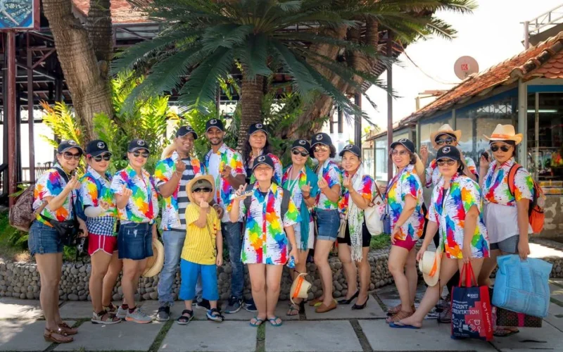 A lively group of adults and a child enjoying a sunny day outdoors in colorful matching shirts.