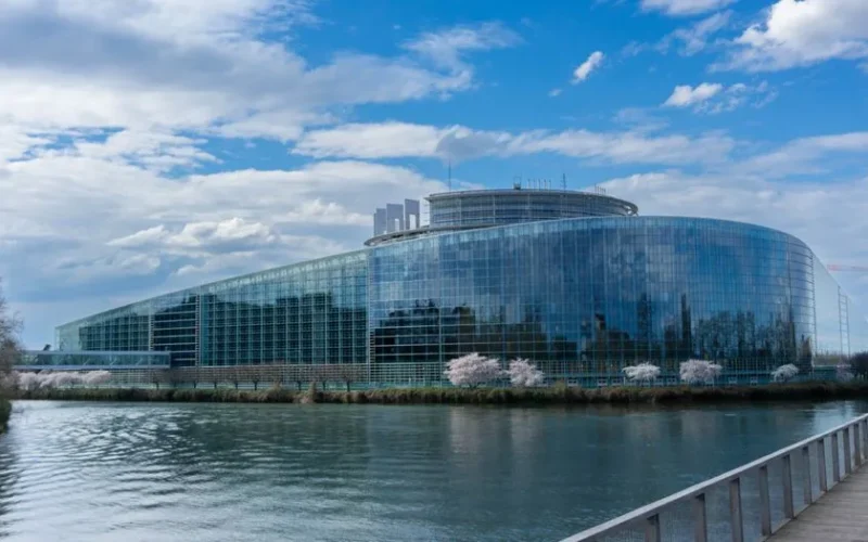 Modern architecture of the European Parliament building in Strasbourg with a reflective glass facade and river view.