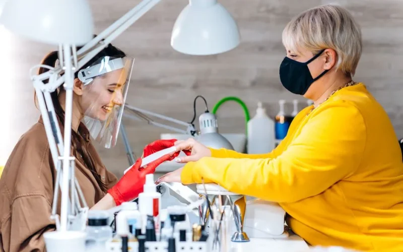 Clients receive manicures with safety measures in place at a modern salon.