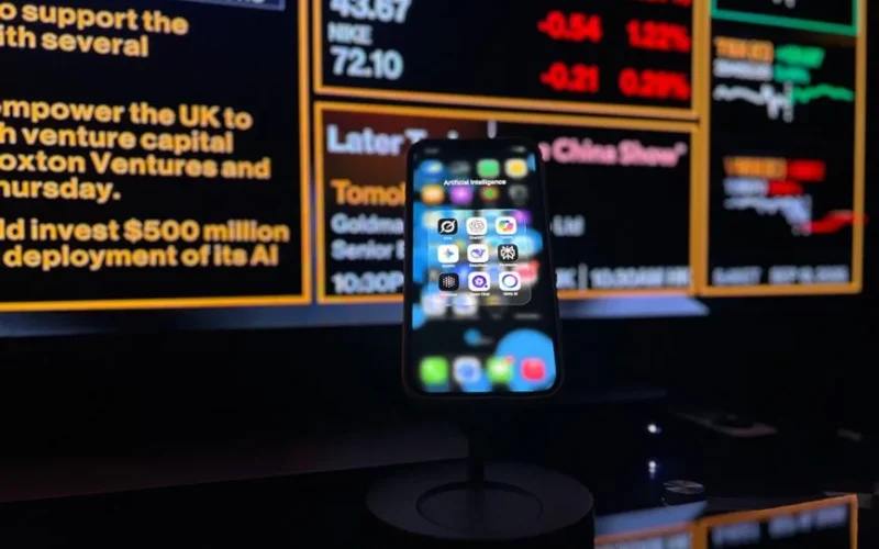 Smartphone displaying AI apps in front of a financial data screen in London.