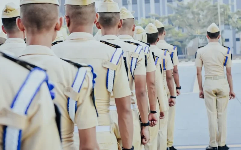 A group of soldiers in formal uniforms standing in a line at an outdoor military ceremony.