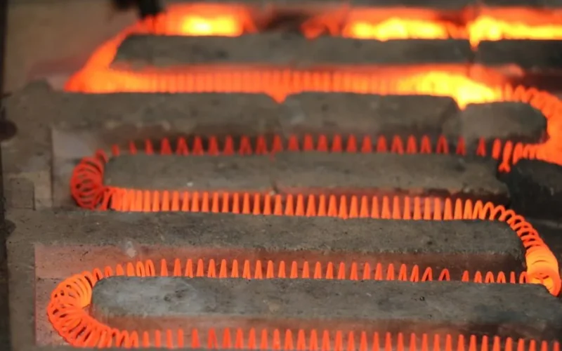 Detailed view of a glowing electric heating element with a coiled structure emitting heat.