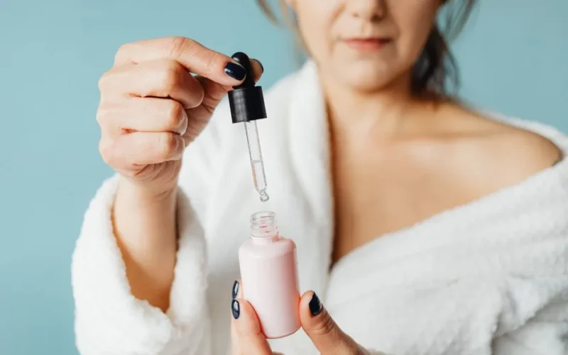 Close-up of an adult woman applying serum with a pipette indoors.